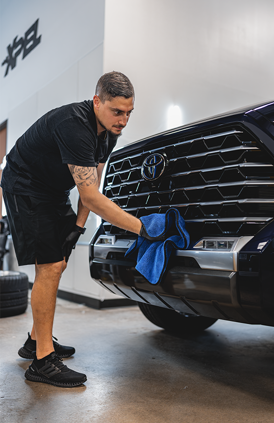 person cleaning truck front grill