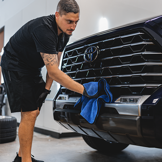 Person cleaning car front grill